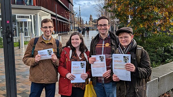 A group of 4 Lib Dem activists holding up Glasgow resident surveys
