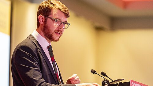 Daniel O'Malley at a podium speaking.